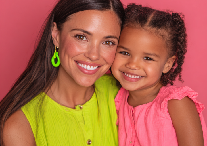 Mother and daughter smiling together on a pink background